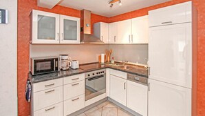 Eine kleine Küche mit weißen Schränken, einer Mikrowelle, einer Kaffeemaschine, einem Toaster und einem Spülbecken.