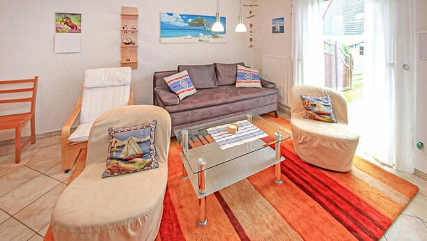 Ein Wohnzimmer mit einer Couch, zwei Sesseln, einem Couchtisch und einem Holzregal.