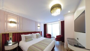 A hotel room with a large bed, a desk, a TV, and a chandelier. - Golden Horn Bosphorus Hotel  (Istanbul)