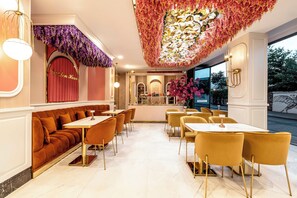 Um restaurante com um arco vermelho, área de bar e disposição de mesas e cadeiras.