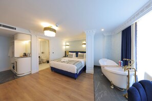 Ein Hotelzimmer mit einem großen Bett, einem eigenen Badezimmer mit Badewanne und einem begehbaren Kleiderschrank.