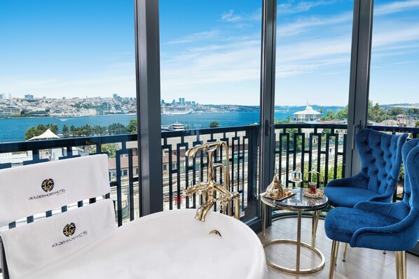 A balcony with a view of a cityscape and the sea, a bathtub, and a blue chair. - Golden Horn Bosphorus Hotel  (Istanbul)