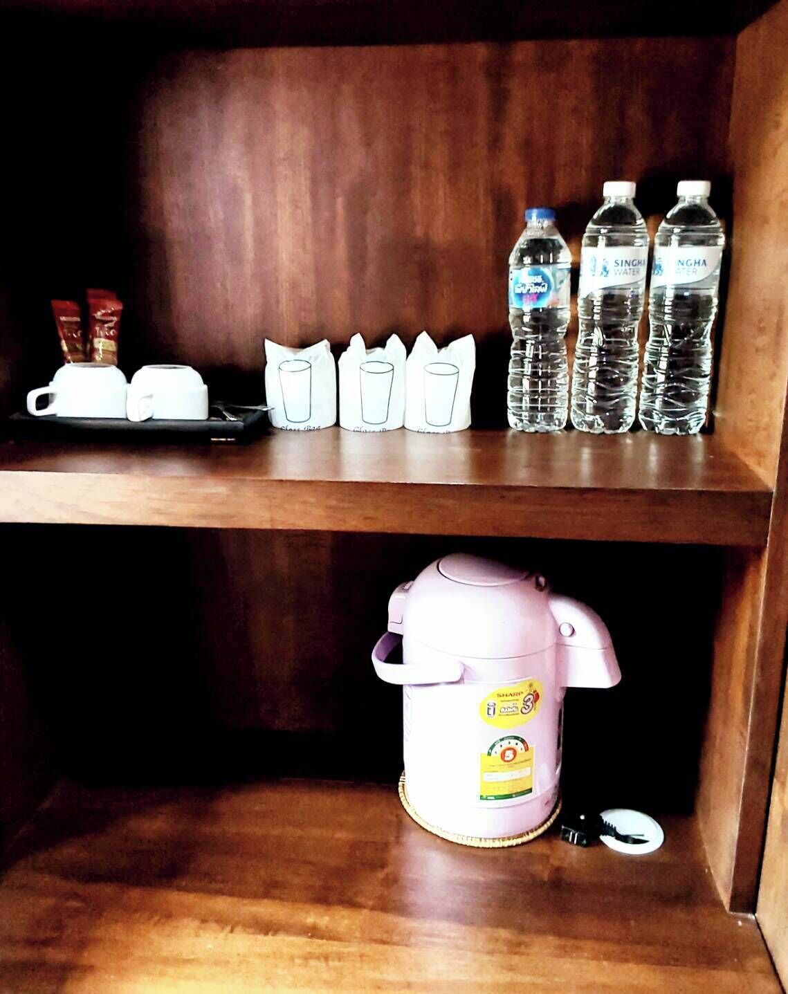 A shelf with two white cups, three paper cups, and four water bottles.