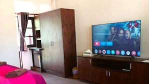 A hotel room with two beds, a TV, a wardrobe, and a small table.