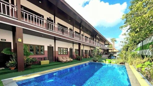 A hotel with a swimming pool, a covered outdoor area, and a two-story building with balconies.