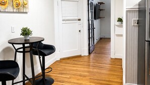 A kitchen with a wooden floor, a refrigerator, a dining area with a table and chairs, and a painting on the wall. - Central Dog-Friendly Apartment | Office (Saint Louis)