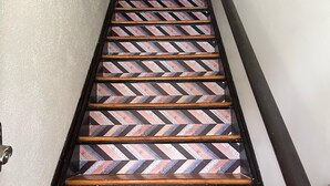 A staircase with wooden steps and a chevron-patterned floor. - Central Dog-Friendly Apartment | Office (Saint Louis)