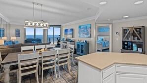 A spacious kitchen with a dining area, a large window overlooking the ocean, and a view of the beach. - Phoenix 8 903 | Indoor, Outdoor Pools | Beachfront | Tennis | My Beach Getaways (Orange Beach)