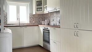 Una cocina con armarios blancos, horno empotrado y ventana.