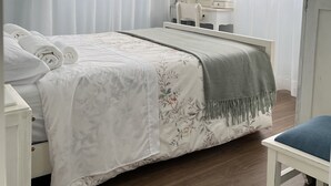 Un dormitorio con una cama, una mesita de noche, una silla, un aparador y un espejo.