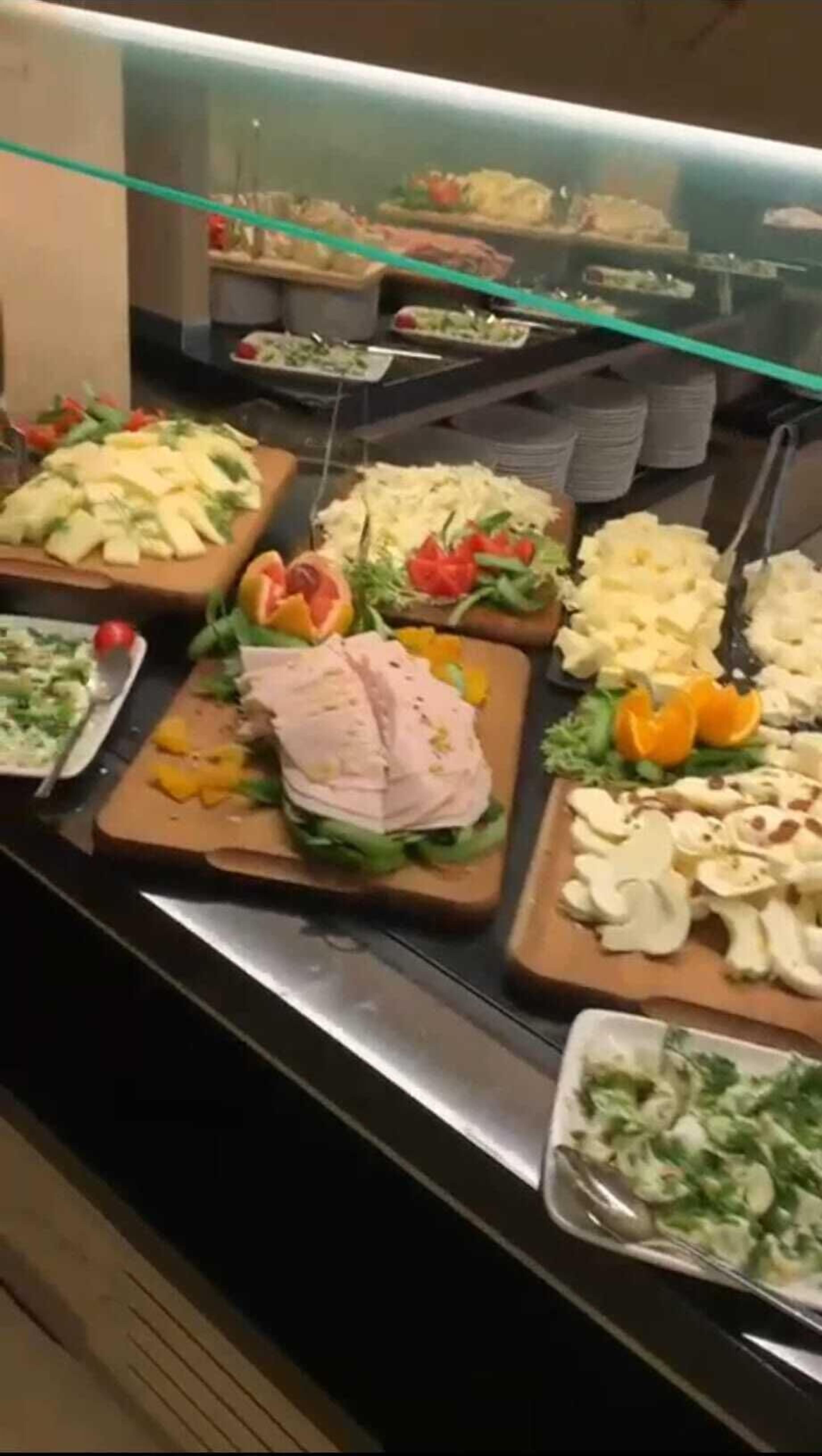 Un bufé con diferentes opciones de comida, incluyendo carnes cortadas, ensaladas y frutas.