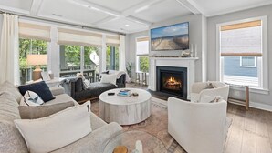 A spacious living room with a fireplace, comfortable seating, and large windows offering views of the outdoors. - 5BR Beauty Near Bethany-Community Pool; Linens (Ocean View)