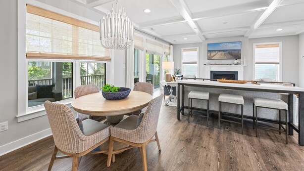 A modern kitchen with a round dining table, wicker chairs, a chandelier, and a fireplace. - 5BR Beauty Near Bethany-Community Pool; Linens (Ocean View)