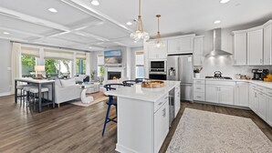 A modern kitchen with white cabinetry, a large island, stainless steel appliances, and pendant lighting. - 5BR Beauty Near Bethany-Community Pool; Linens (Ocean View)
