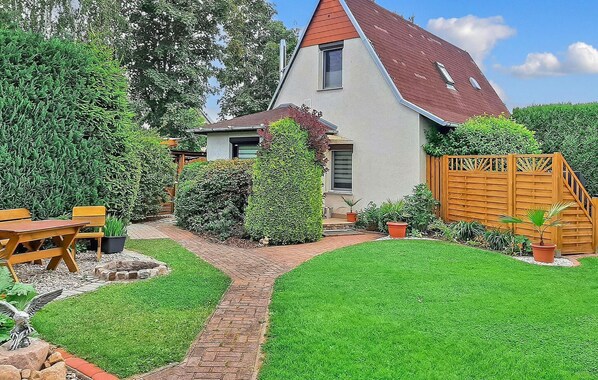 Ein Haus mit einem geneigten Dach, einem Ziegelweg, der zur Haustür führt, und einem gepflegten Rasen.