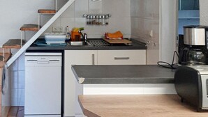Een compacte keuken met een vaatwasser, een koffiezetapparaat en een klein aanrecht.