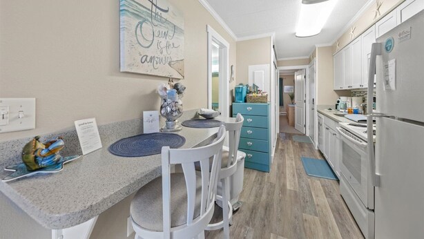 A kitchen with a granite countertop, white chairs, a blue cabinet, and a refrigerator. - Private Pool Steps From the Beach (Ocean City)