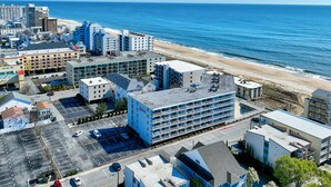 A coastal urban area with modern buildings, a parking lot, and a beach in the background. - Private Pool Steps From the Beach (Ocean City)