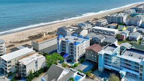 Un hotel costero con varias construcciones, estacionamiento y vista a la playa.