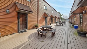 Eine Holzterrasse mit Picknicktischen und Kübelpflanzen.