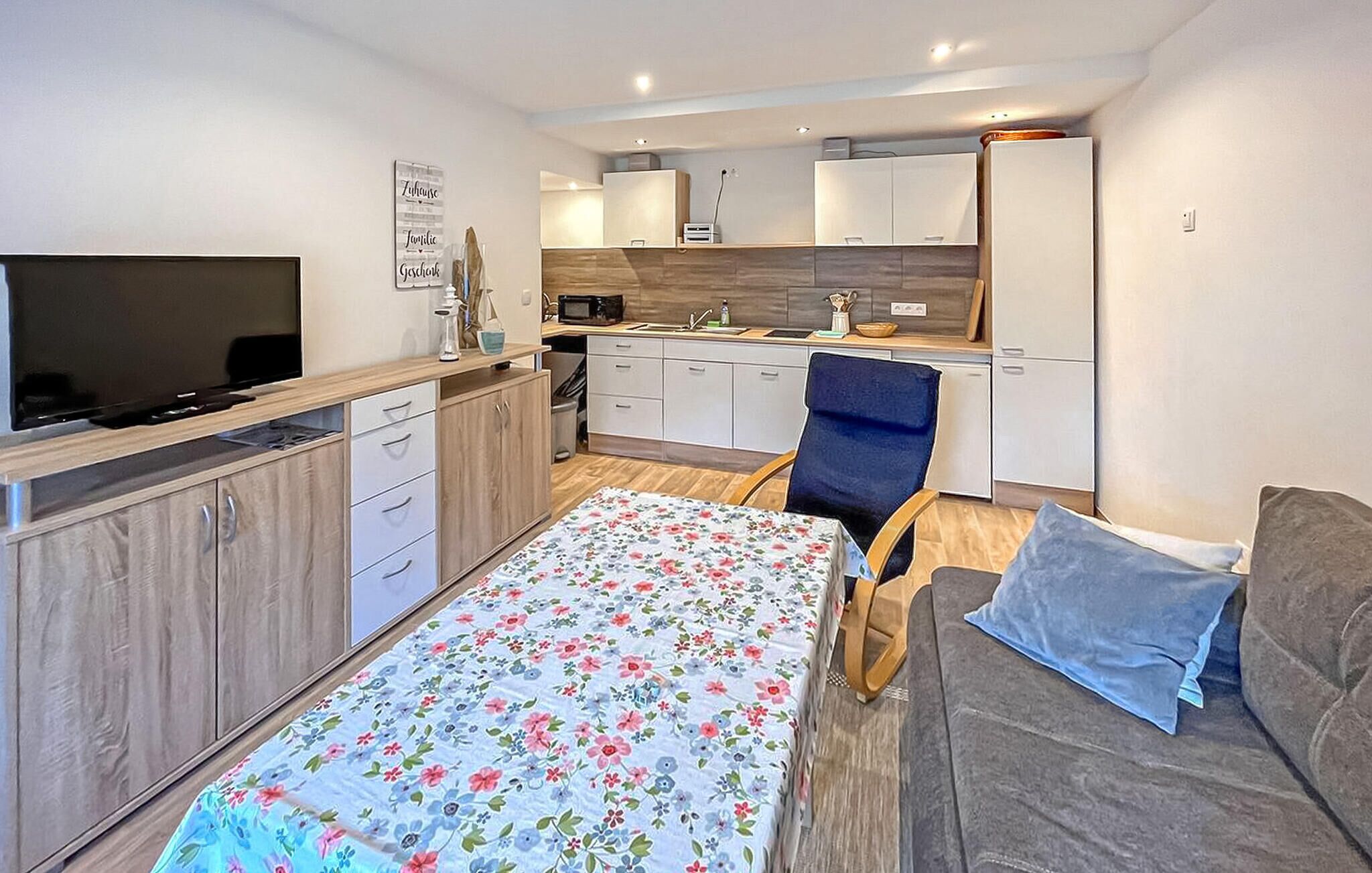 Een knus woongedeelte met een bed, een slaapbank, een televisie, een kitchenette en een eethoek.