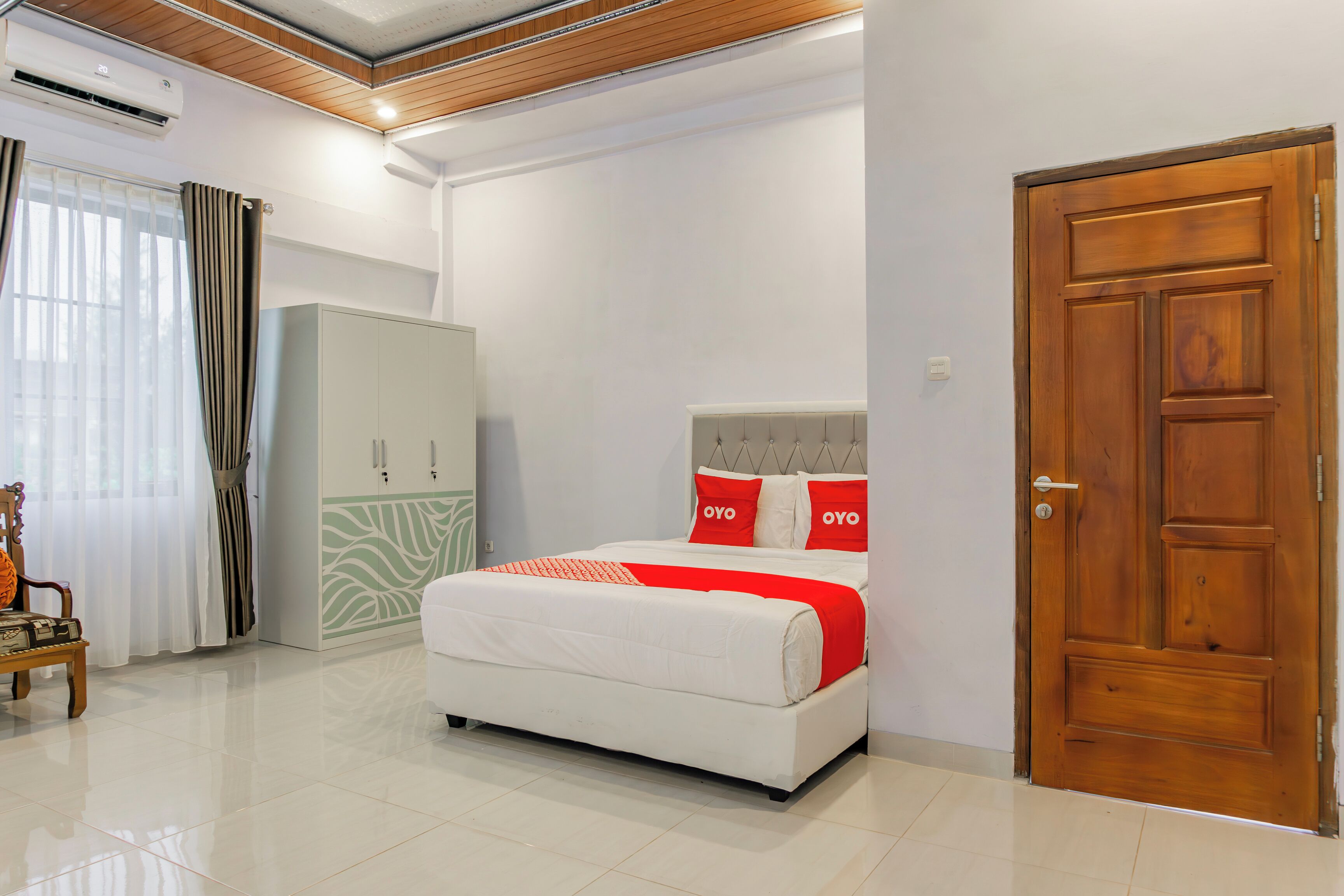A modern bedroom with a large bed, a wardrobe, and a wooden door.
