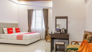 A hotel room with a bed, a desk, a chair, a mirror, and a window with curtains. - Hotel O Tebing Vieatnam (Bandar Lampung)