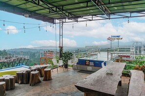 A terrace with a view of the sea and mountains, featuring a table, chairs, and a sign for 'TEBING VIETNAM'. - Hotel O Tebing Vieatnam (Bandar Lampung)