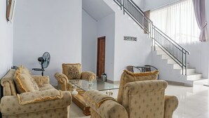 A living room with a sofa set, a glass coffee table, a fan, and a staircase. - Hotel O Tebing Vieatnam (Bandar Lampung)