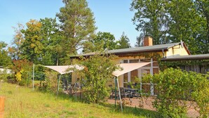 Een huis met een patio, omringd door bomen en een hek.