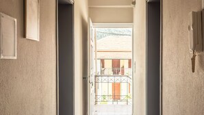 A hallway with a tiled floor leading to an open balcony with a view of a building. - Blue Hug Apartments  (Igoumenitsa)