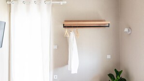 A bathroom with a shower curtain, a towel hanging on a rack, a wooden shelf, a potted plant, and a wall-mounted light fixture. - Blue Hug Apartments  (Igoumenitsa)
