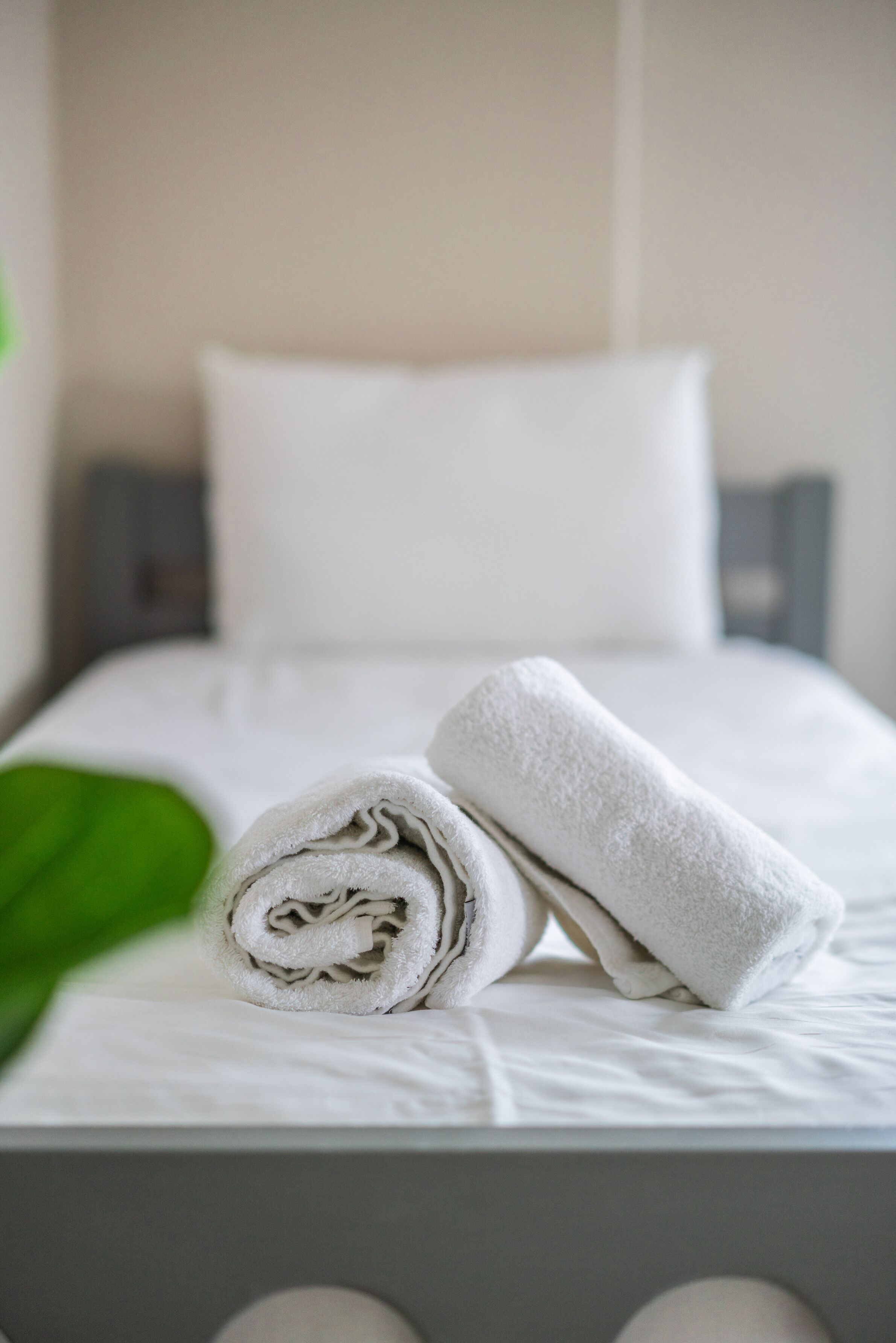 Un lit bien fait, avec des draps blancs et une serviette enroulée posée sur le dessus.