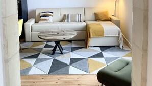 A modern living room with a sofa, a coffee table, and a green ottoman. There are framed pictures on the wall and a lamp on the side. - Entre Loire et Château (Amboise)