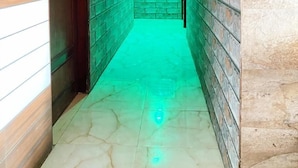 A hallway with patterned walls and a green-lit ceiling. - Manali Hotel By GRB (New Delhi)