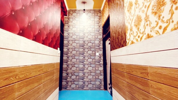 A narrow hallway with a stone wall at the end, wooden paneling on the sides, and a blue carpet leading to a door. - Manali Hotel By GRB (New Delhi)