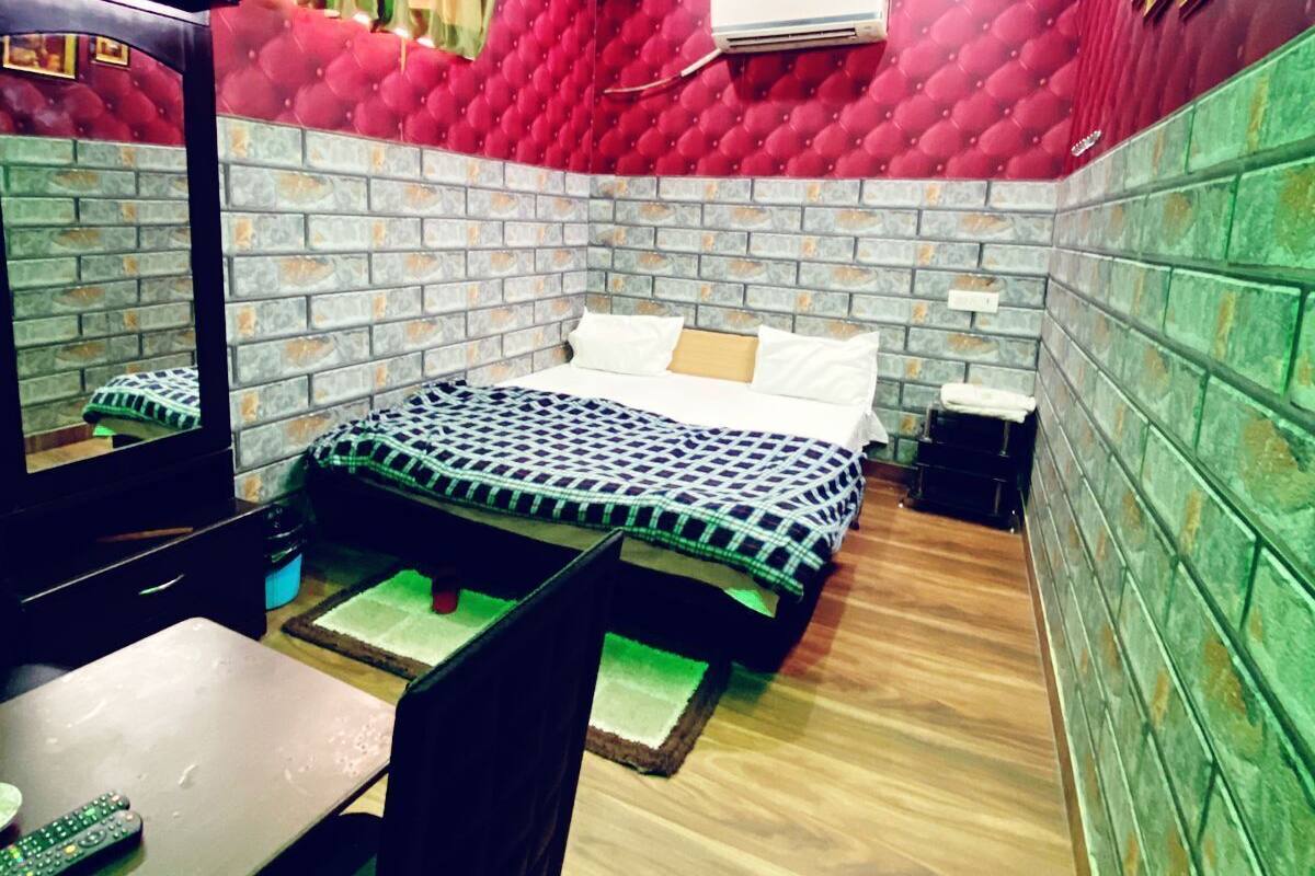 A bedroom with a bed, a desk, a chair, a ceiling fan, and a TV.
