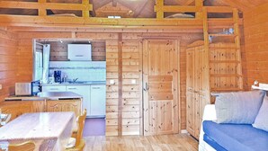 En stuga med träpanel p å insidan, innehållande ett kök, en matplats och ett sovområde.