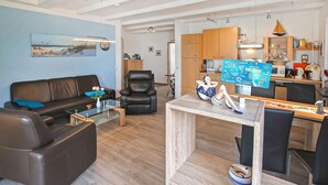 En moderne stue med en sort lædersofa, et glasbord og et træsidebord med en dekorativ genstand.