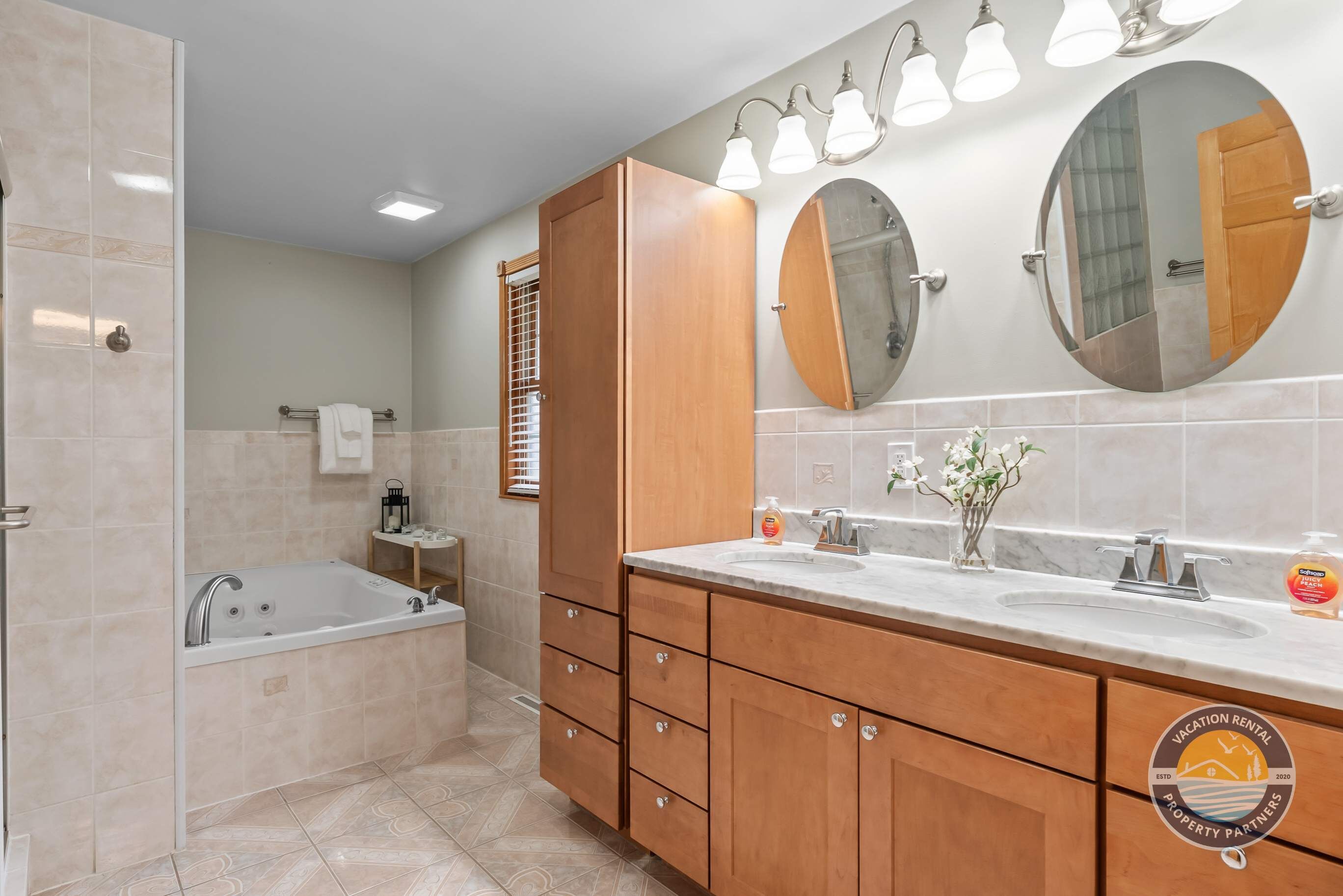 A modern bathroom with a bathtub, double vanity with a mirror, and a shower.