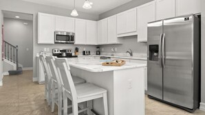 A modern kitchen with white cabinetry, stainless steel appliances, and pendant lighting. - Fortebello Beachside 152 (Indian Harbour Beach)