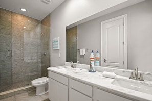 A modern bathroom with a large vanity, a shower, and a toilet.
