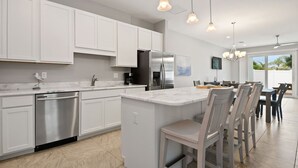 A modern kitchen with white cabinetry, stainless steel appliances, and pendant lighting. - Fortebello Beachside 152 (Indian Harbour Beach)