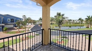 A balcony with a view of a residential area, a pond, and a blue house. - Fortebello Beachside 154 (Indian Harbour Beach)