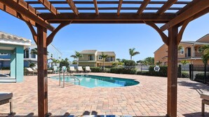 A pool area with a pergola, lounge chairs, and a brick patio. - Fortebello Beachside 154 (Indian Harbour Beach)