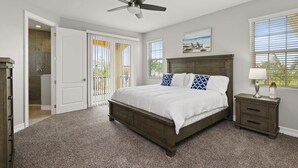 A bedroom with a bed, a ceiling fan, a nightstand, a window, and a door. - Fortebello Beachside 154 (Indian Harbour Beach)