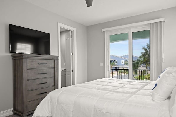 Un dormitorio con cama, cómoda, televisor y balcón con vistas.