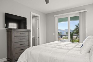 A bedroom with a bed, a dresser, a TV, and a balcony with a view. - Fortebello Beachside 156 (Indian Harbour Beach)