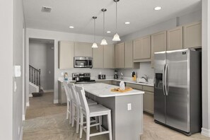 A modern kitchen with a central island, stainless steel appliances, and pendant lighting.