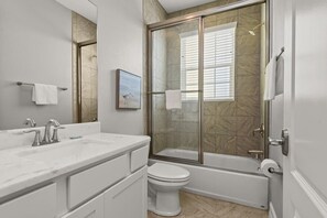 A bathroom with a glass-enclosed shower, a toilet, a sink with a mirror, and a towel rack.
